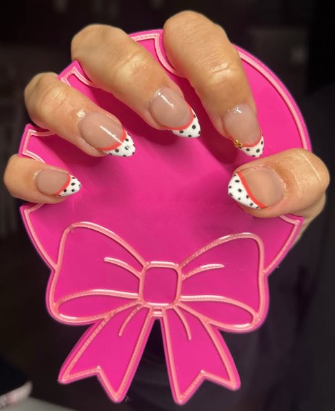 Almond nails with white polka-dot French tips and a thin red outline, by Leighton